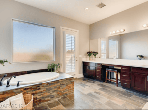 Spacious bathroom featuring a large window, double vanity, and elegant decor.